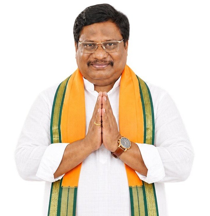 Aelleni Sudhakar Rao greeting with folded hands, wearing a saffron and green scarf